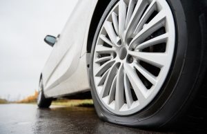 Car parked on the side of the road with a flat tire in need of emergency tire repair.