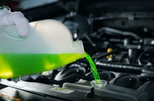 Pouring new coolant into a car engine radiator before taking a long drive.