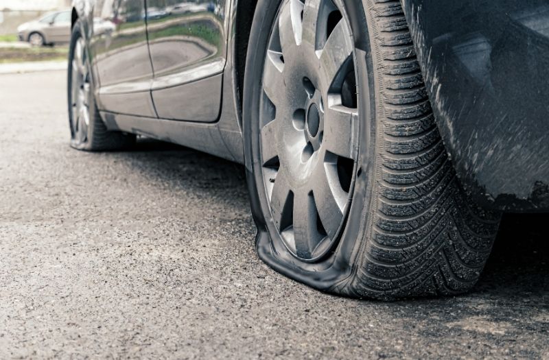 Close up of a flat tire on a black car.